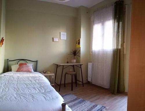 Schlafzimmer mit einem Bett, einem Tisch und einem Fenster in der Unterkunft άνετο, φωτεινό και ήσυχο για οικογένεια Ιθάκης - Ιthakis 8 Πυλαία in Thessaloniki