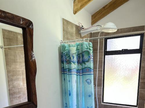 a shower curtain in a bathroom with a window at Rincón Entre Piedras in Choachí