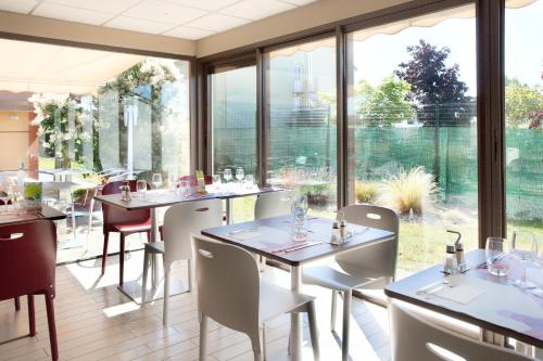 a restaurant with tables and chairs and large windows at Campanile Tours Sud - Chambray-Les-Tours in Chambray-lès-Tours