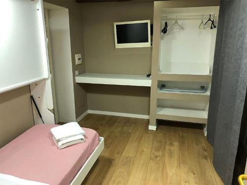 Habitación pequeña con cama rosa y TV. en B&B Napoli Centro Storico, en Nápoles