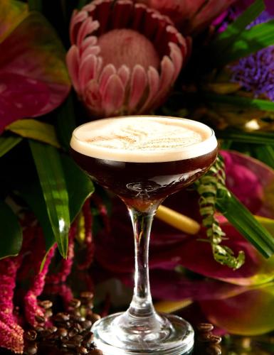 a drink in a wine glass on a table with flowers at Crowne Plaza Dublin Blanchardstown by IHG in Blanchardstown