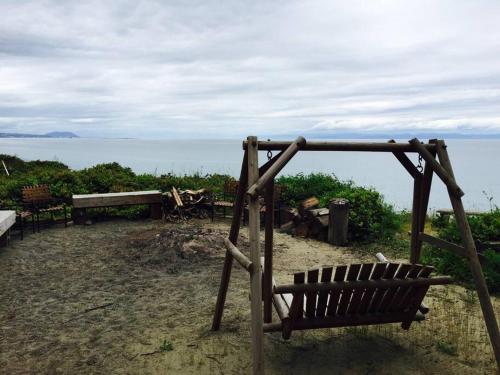 a wooden bench sitting on top of a beach at Treehouse-Small Eagles Perch over the water in Port Angeles