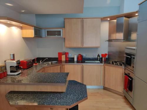 uma cozinha com armários de madeira e bancadas de granito em West End & EICC with Parking em Edinburgo