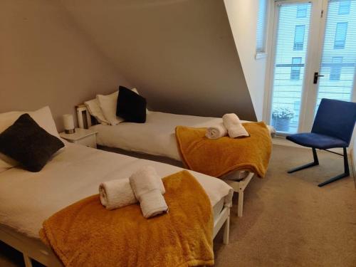 a bedroom with two beds and a blue chair at West End & EICC with Parking in Edinburgh