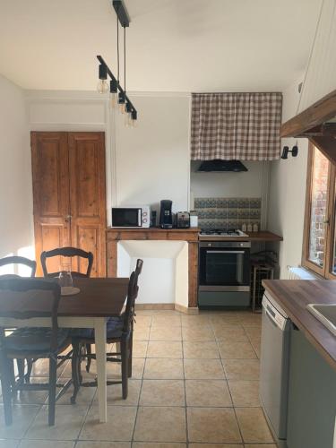 une cuisine avec une table, des chaises et une cuisinière dans l'établissement Maison de ville au bord de la rivière !, à Beauvais