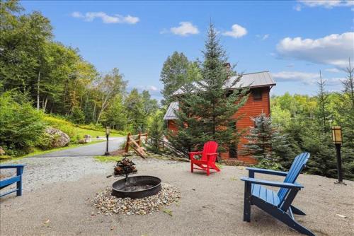 a fire pit with two chairs and a house at Mountain Brook Lodge in Killington