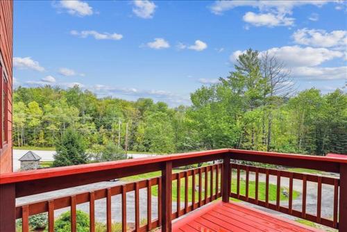 a wooden balcony with a view of the woods at Mountain Brook Lodge in Killington