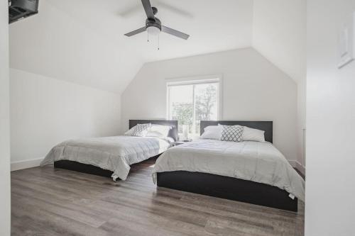 Habitación blanca con 2 camas y ventilador de techo. en Shoreside 4b/4b walkout retreat with perfect sand, en Ottertail