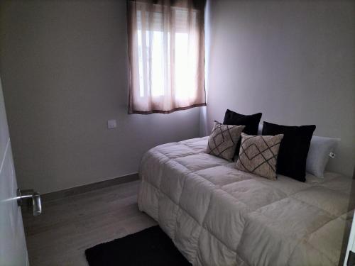 a bedroom with a bed with pillows and a window at Apartamento zafra Cristina in Zafra