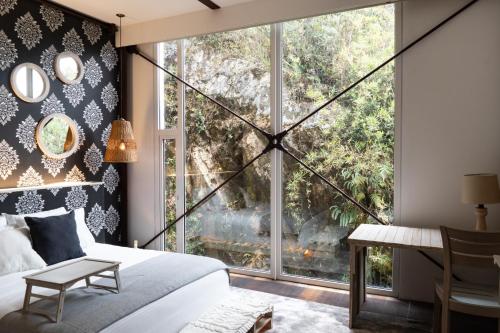 - une chambre avec un lit et une grande fenêtre dans l'établissement Sukha Resort, à La Calera