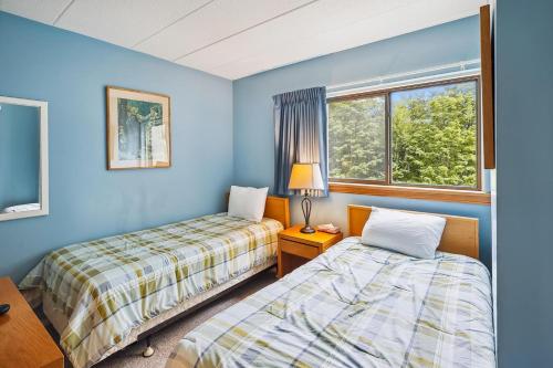 two beds in a room with blue walls and a window at Pinnacle E07 in Killington