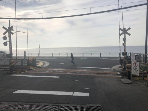 a person walking on a road near the ocean at 都心の家30 square meter king size bed, step meter, 3-person room201 in Tokyo