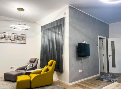 a living room with a yellow chair and a tv at Apartman ''Silver fox'' Bjelašnica in Bjelašnica
