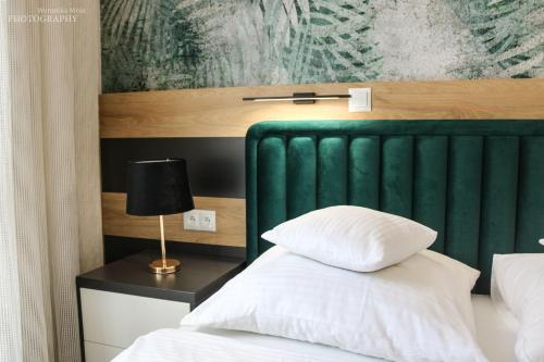 łóżko z zielonym zagłówkiem oraz stół z lampką w obiekcie D Apartments Centrum Prowiantowa w mieście Białystok