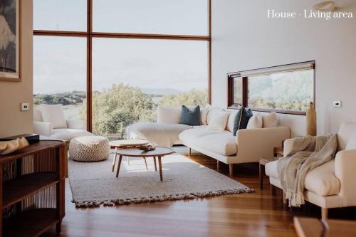 a living room with white furniture and a large window at Miramar Beach House in Seymour