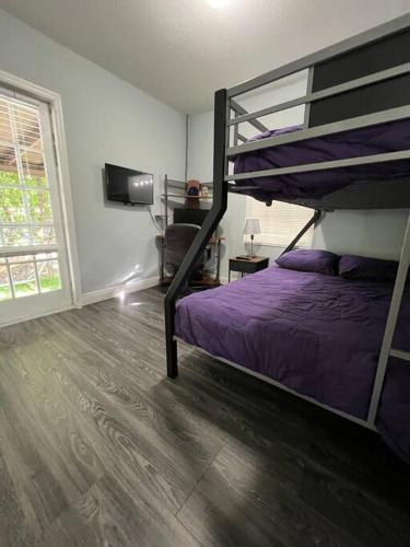 a bedroom with a bunk bed with purple sheets at “La Casita” Beautiful home in the heart of Miami ! in Miami