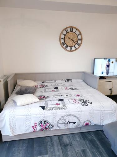 1 dormitorio con 1 cama con reloj en la pared en Appartement studio cosy O fil de l'O à 10 mn de Disney, en Crécy-la-Chapelle