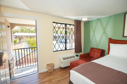 een slaapkamer met een bed, een stoel en een raam bij Travelodge by Wyndham Macon West in Macon