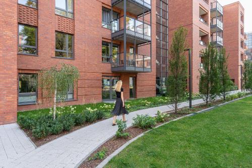 a woman walking down a sidewalk in front of a building at Scala City Center Premium Apartments with Parking by Lion Apartments in Gdańsk