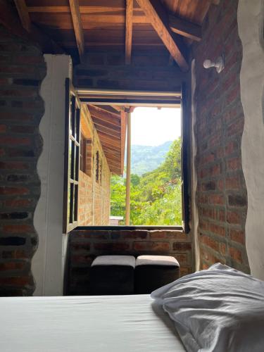 a bed in a room with a large window at Finca Hotel Tierra Verde in Girardota
