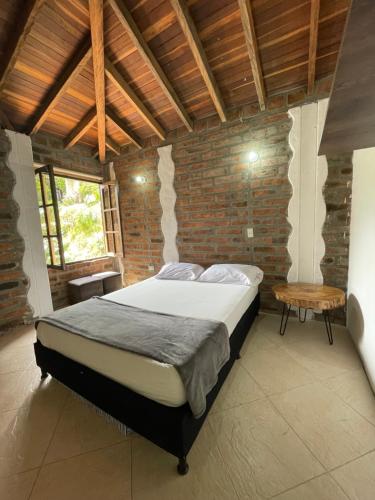 a bedroom with a bed and a brick wall at Finca Hotel Tierra Verde in Girardota