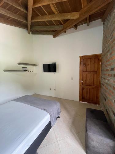 a bedroom with a bed and a flat screen tv at Finca Hotel Tierra Verde in Girardota