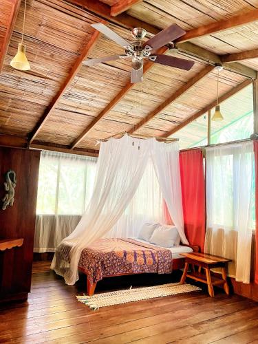 a bedroom with a canopy bed in a room with windows at Ocean Forest Ecolodge in San Pedrillo