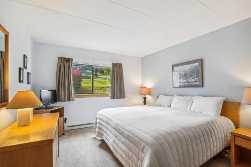 um quarto com uma cama, uma secretária e uma janela em Pinnacle E05 em Killington
