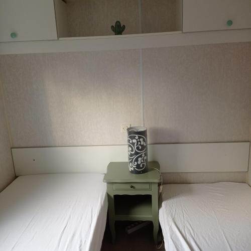 Cette chambre comprend 2 lits et un vase sur une table. dans l'établissement CAMPING LE BEL AIR mobil home LE PALMIER 4 personnes, à Limogne-en-Quercy