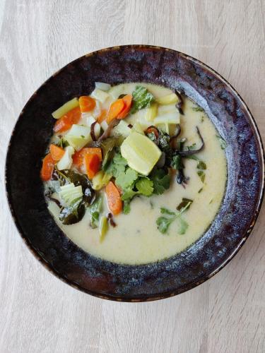 a bowl of soup with vegetables in it on a table at Hôtel Influences La Bresse in La Bresse