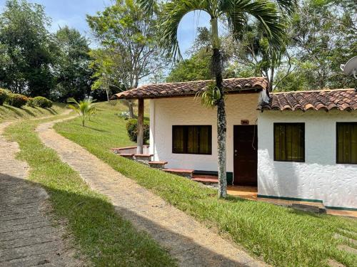 uma casa com uma palmeira ao lado de uma estrada de terra em Hotel Candilejas em Puerto Berrío