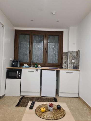 - une cuisine avec des appareils électroménagers blancs et une table dans l'établissement Studio indépendant et bien équipé avec véranda commune, à Neuilly-sur-Marne