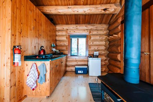 a kitchen in a log cabin with a sink and a refrigerator at Rocky Mountain Escape Log Cabin Rentals - Rock Lake in Rock Lake Provincial Park