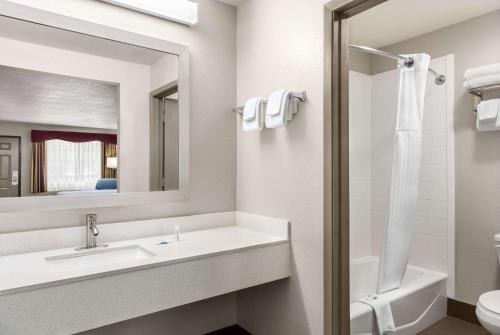 a bathroom with a sink and a toilet and a mirror at Days Inn by Wyndham San Antonio Near Fiesta Park in San Antonio