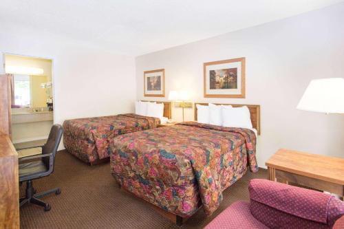 a hotel room with two beds and a desk at Days Inn by Wyndham Dubuque in Dubuque