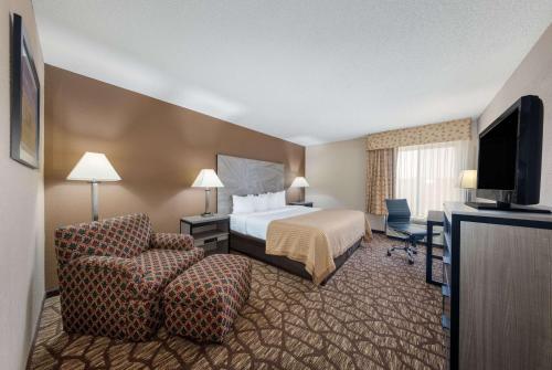 a hotel room with a bed and a chair at Baymont by Wyndham Lawrence in Lawrence