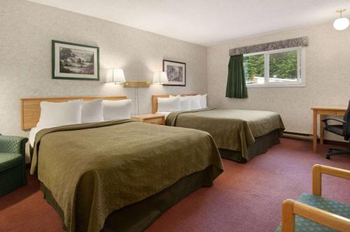 una habitación de hotel con 2 camas y una silla en Travelodge by Wyndham Hope, en Hope