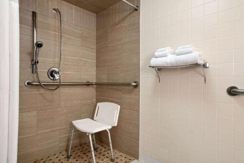 y baño con ducha y silla blanca. en Days Hotel by Wyndham Allentown Airport / Lehigh Valley en Allentown