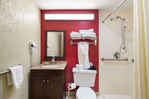 Best Western Braddock Inn في La Vale: حمام به مرحاض أبيض وجدار احمر