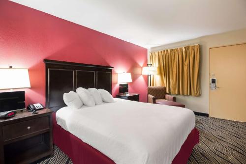 a hotel room with a large bed and a red wall at Best Western Braddock Inn in La Vale