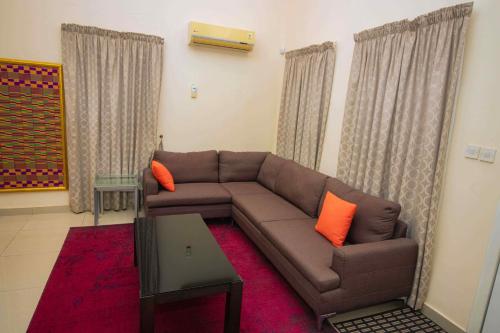 a living room with a brown couch and orange pillows at Brown Hills Residences in Aburi