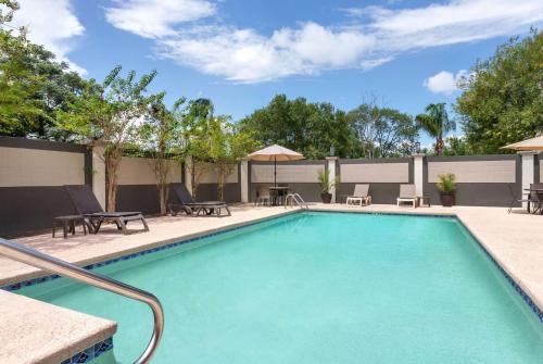 una piscina con sillas y sombrillas en un complejo en La Quinta by Wyndham Brownsville North en Brownsville