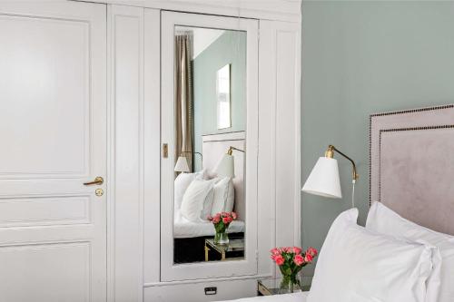 a bedroom with a mirror and a bed with flowers at Hotel Esplanade, BW Signature Collection in Stockholm