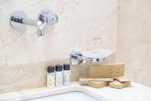 a bathroom with a sink with products on a shelf at Hotel Solum Roof Top in Tbilisi City