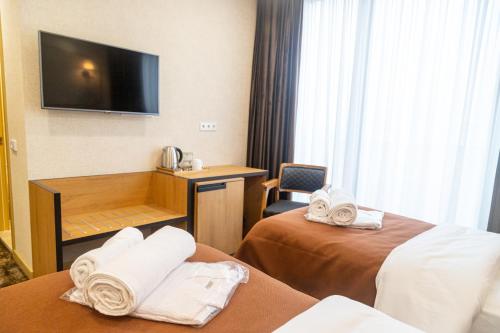 a hotel room with two beds and a flat screen tv at Hotel Solum Roof Top in Tbilisi City