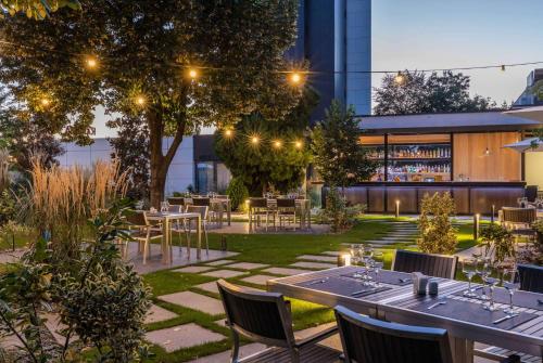 un restaurante con mesas y sillas en un jardín por la noche en Ramada by Wyndham Slatina Parc, en Slatina