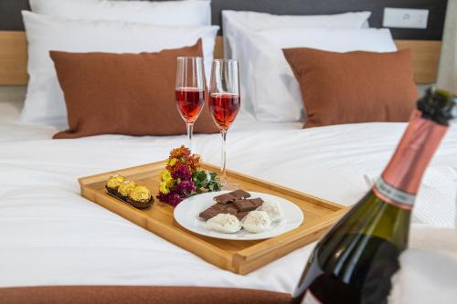 a tray of food and two glasses of wine on a bed at Hotel Solum Roof Top in Tbilisi City