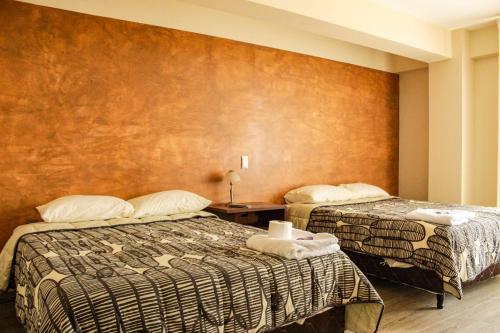 a hotel room with two beds and a wall at Hostal Sky in Tarija