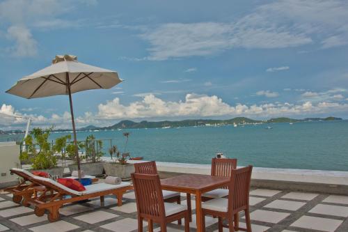 a table and chairs with an umbrella and the ocean at Raya Beachloft in Rawai Beach