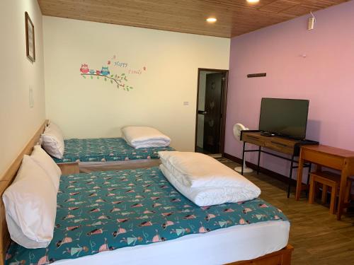 two beds in a room with a television and a desk at Tianen Farm in Hualing
